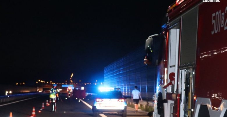 Na zdjęciu miejsce wypadku na autostradzie A1 , widoczny policyjny radiowóz na sygnale, policjant w trakcie czynności i wóz strażacki