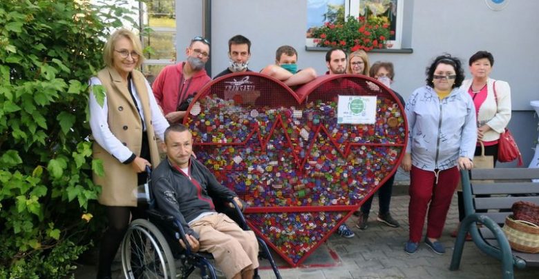 Czerwone metalowe serce na plastikowe nakrętki. Obok uczestnicy i pracownicy Warsztatów Terapii Zajęciowej. Fot. L. Tyl/UM Rybnik