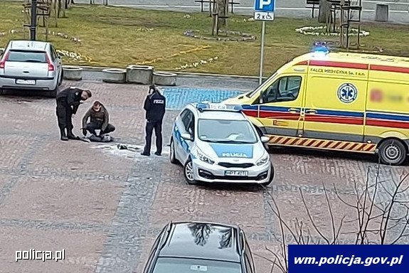 Miejsce zdarzenia. Stojący na placu policjanci obok radiowozu i karetki