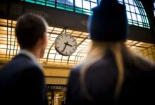 Zmiana Czasu zegar o sylwetki dwóch osób na dworcu kolejowym