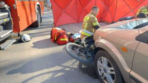 wypadek rowerzysty rower przygnieciony przez samochód obok strażak udzielający pomocy