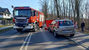 wypadek rowerzysty rower przygnieciony przez samochód obok strażak udzielający pomocy