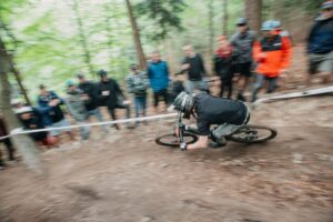Puchar Świata UCI Enduro i Downhill mężczyzna na rowerze zjeżdża z góry w lesie w tle widać kibicó