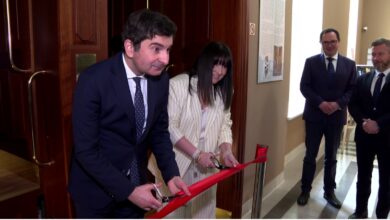 W tle winda paciorkowa, kobieta i mężczyzna przecinają wstęgę.