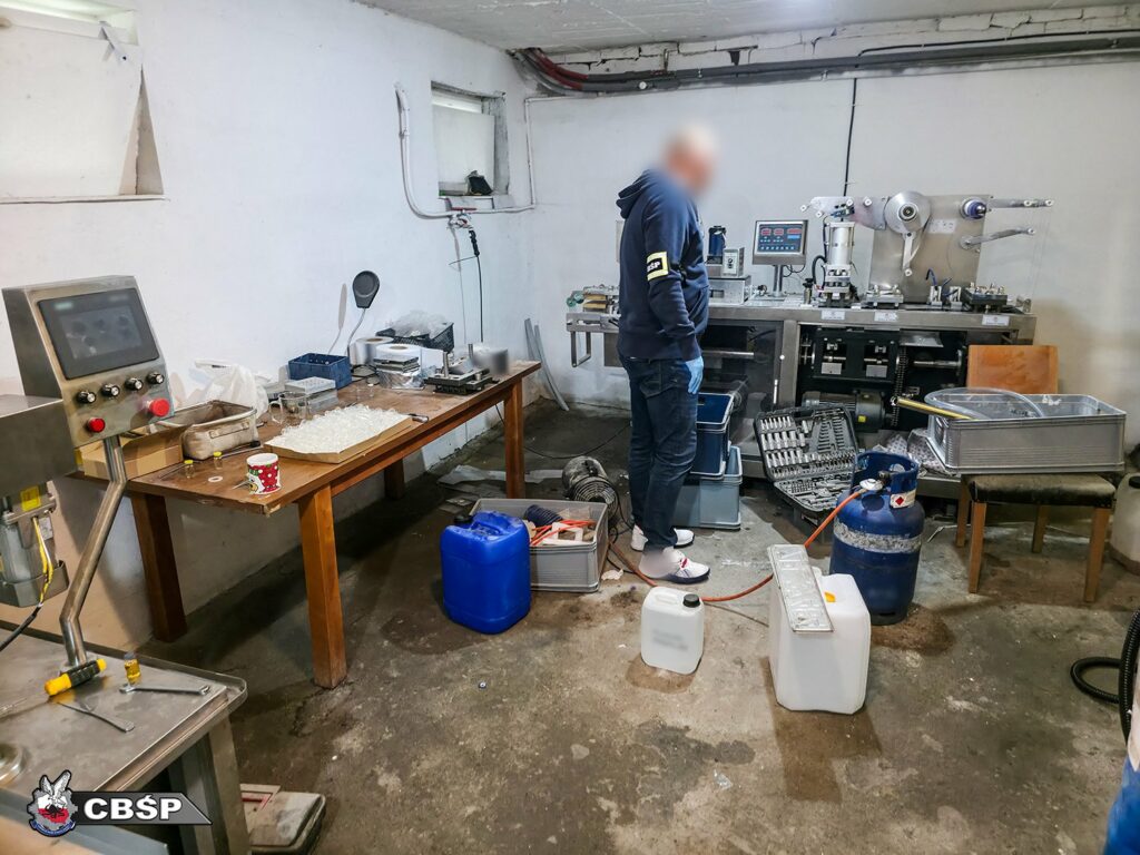 nielegalna fabryka leków policjant przy stołach z odczynnikami