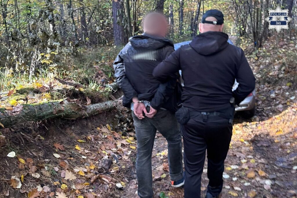 Policjant w lesie prowadzi zatrzymanego mężczyznę